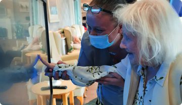 Elderly woman and nurse interacting with G-Touch interactive display care solution